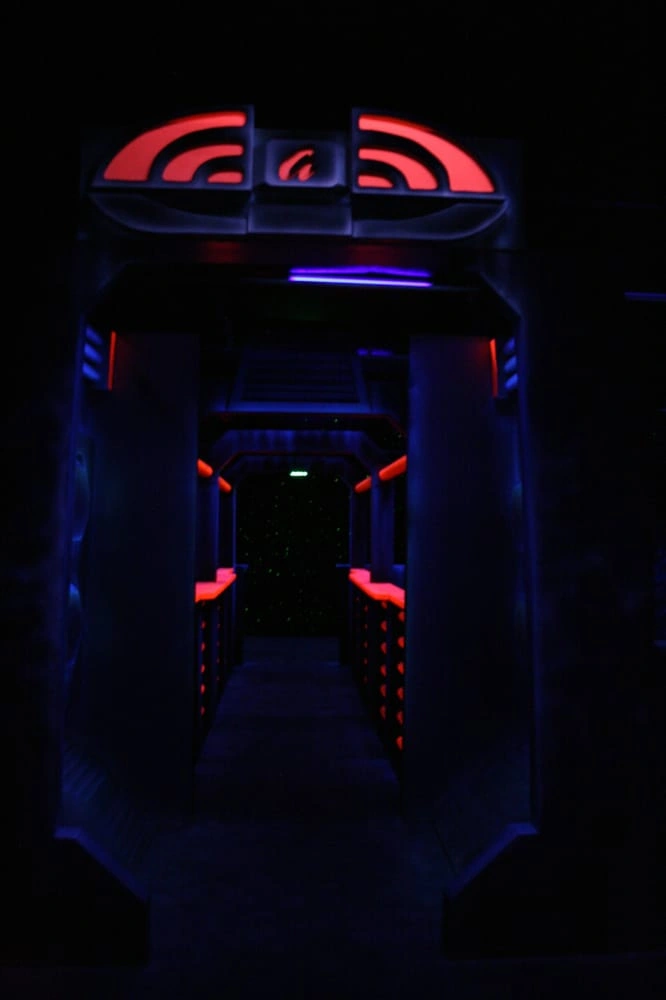 Dark futuristic corridor lit with red and blue neon — immersive environment for all-night laser tag sessions.