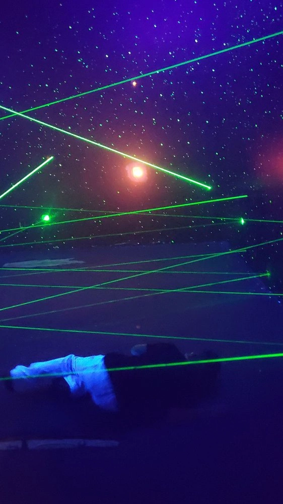 Person lying down to crawl under laser grid beams in the maze